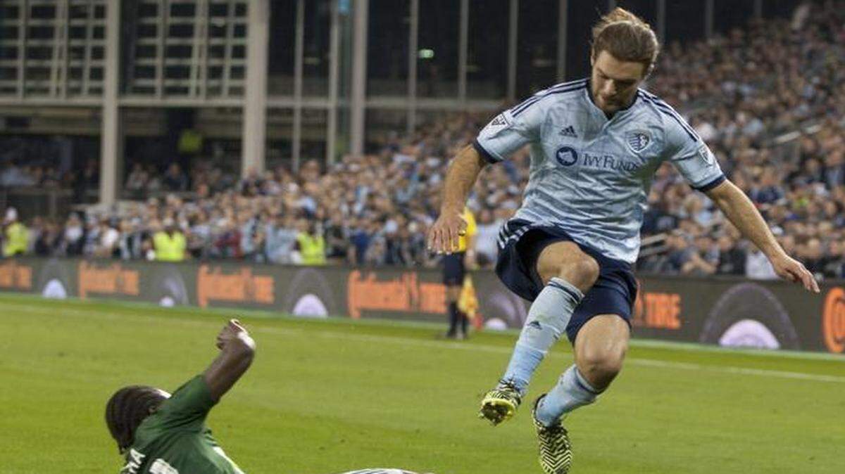 
Midfielder Graham Zusi leaped over the sliding tackle of Portland’s Diego Chara during a game on March 21.
