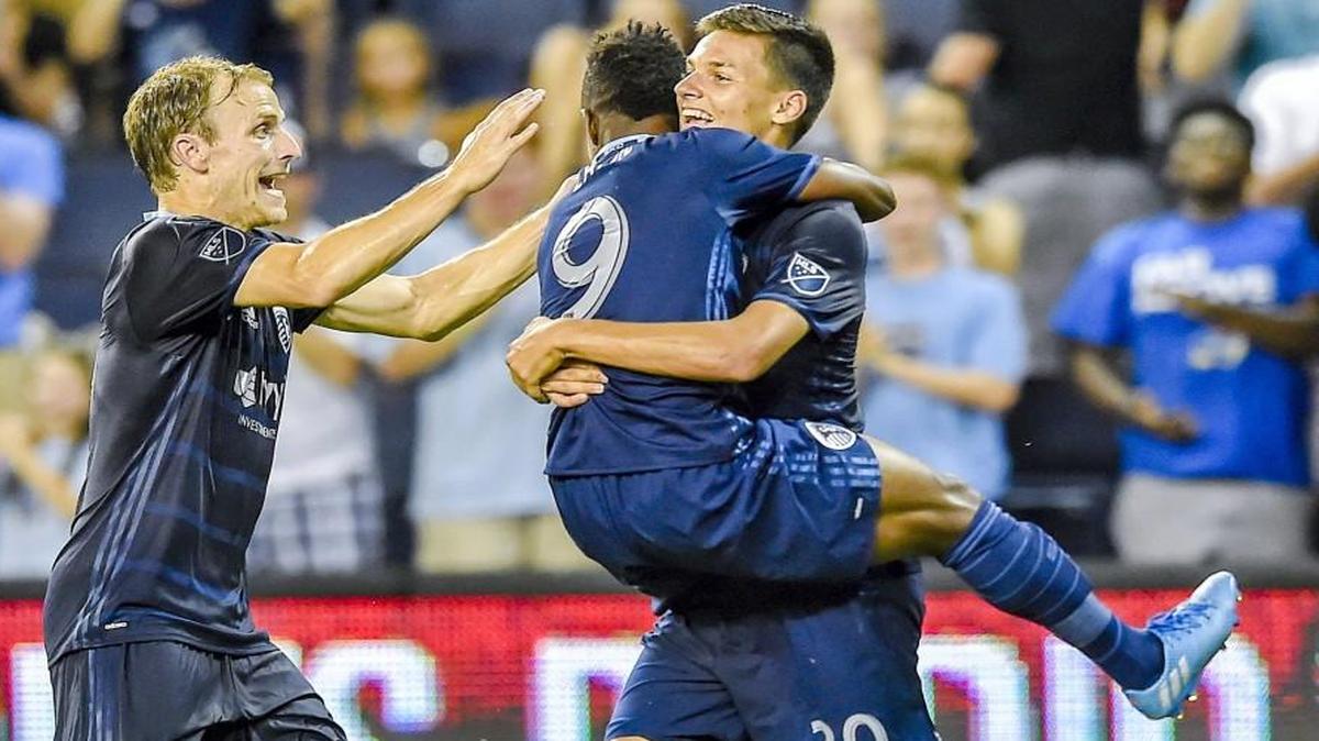 After scoring a goal, Sporting Kansas City forward Daniel Salloi was hugged by teammate Latif Blessing as defender Seth Sinovic joined the celebration during Wednesday’s win.