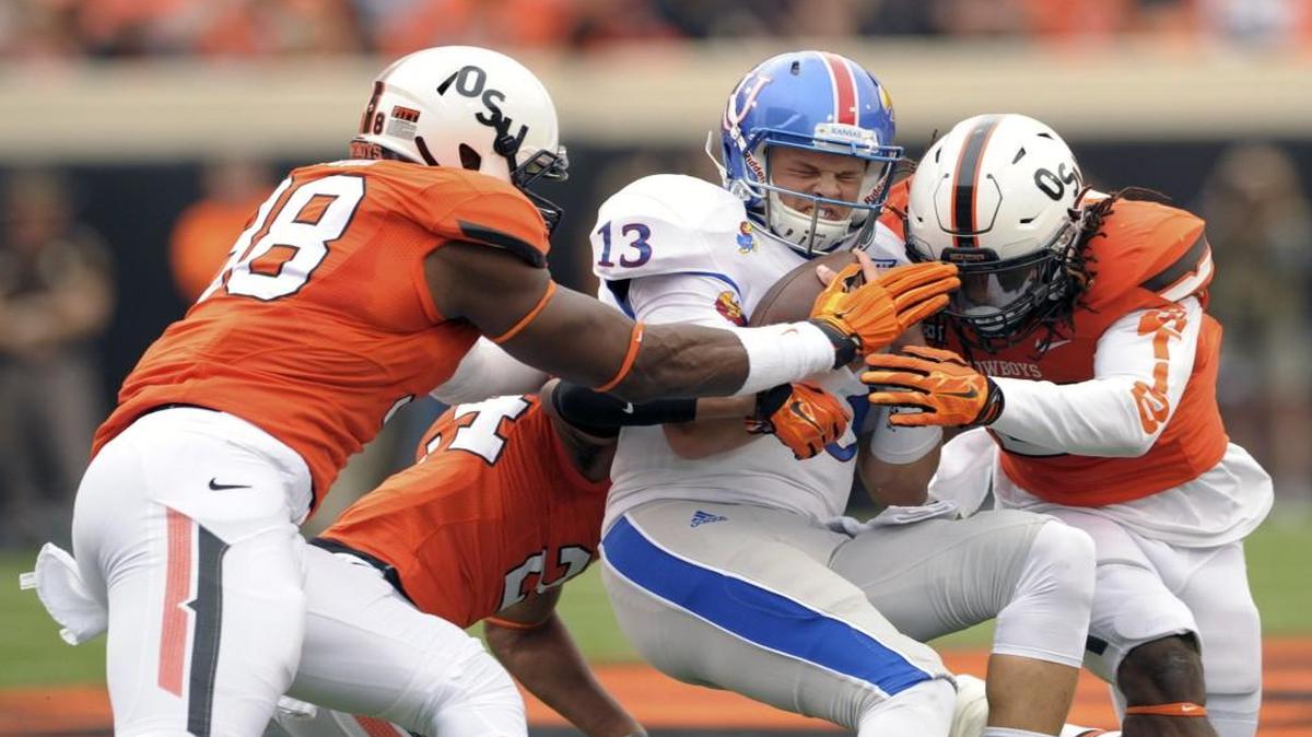 A trio of Oklahoma State defenders tackled Kansas quarterback Ryan Willis during Saturday’s game.