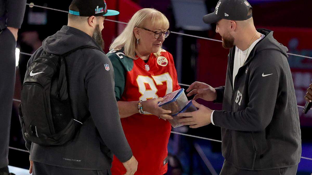 Mother Donna Kelce gives cookies to her sons Jason Kelce (left) of the Philadelphia Eagles and Travis Kelce of the Kansas City Chiefs during Super Bowl LVII Opening Night in Phoenix, Arizona.
