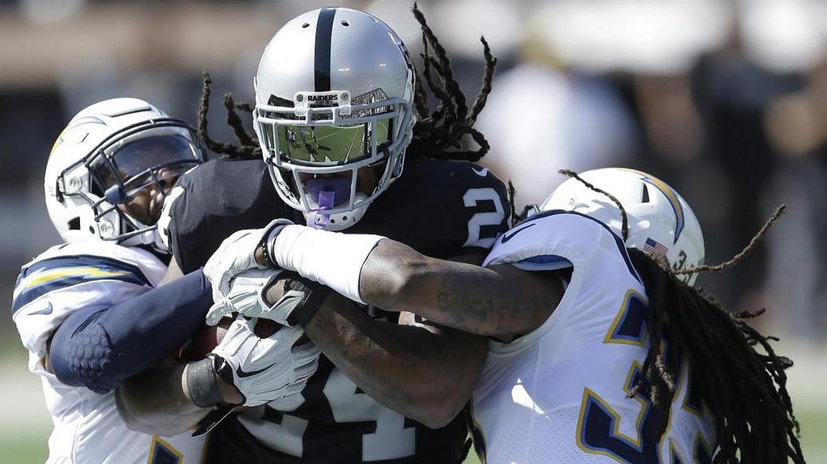 Oakland Raiders running back Marshawn Lynch was tackled by Los Angeles Chargers strong safety Adrian Phillips (left) and free safety Tre Boston during Sunday’s game.