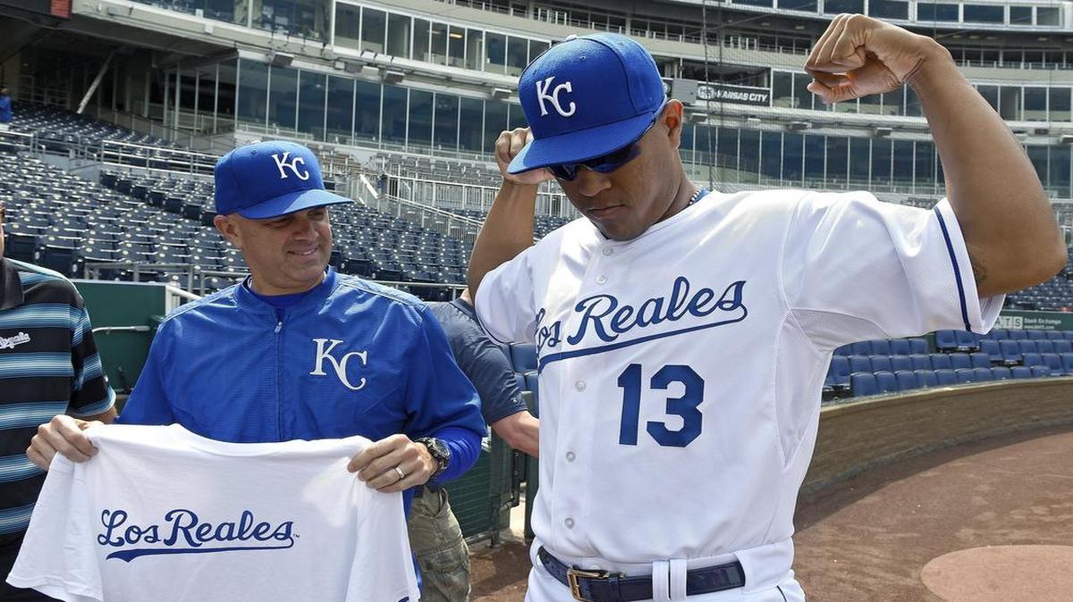 
In May, Kansas City Royals catcher Salvador Perez modeled the Los Reales game jerseys the team was going to wear on Saturday. At left, coach Pedro Grifol held a T-shirt with Los Reales written across it that was be given out in May.
