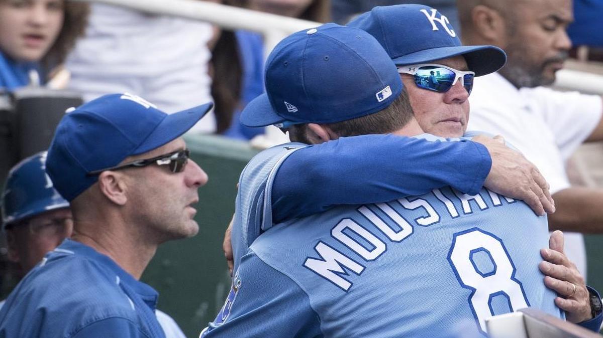 Kansas City Royals third baseman Mike Moustakas hugged manager Ned Yost as hitting coach Dale Sveum looked during Sunday’s game..