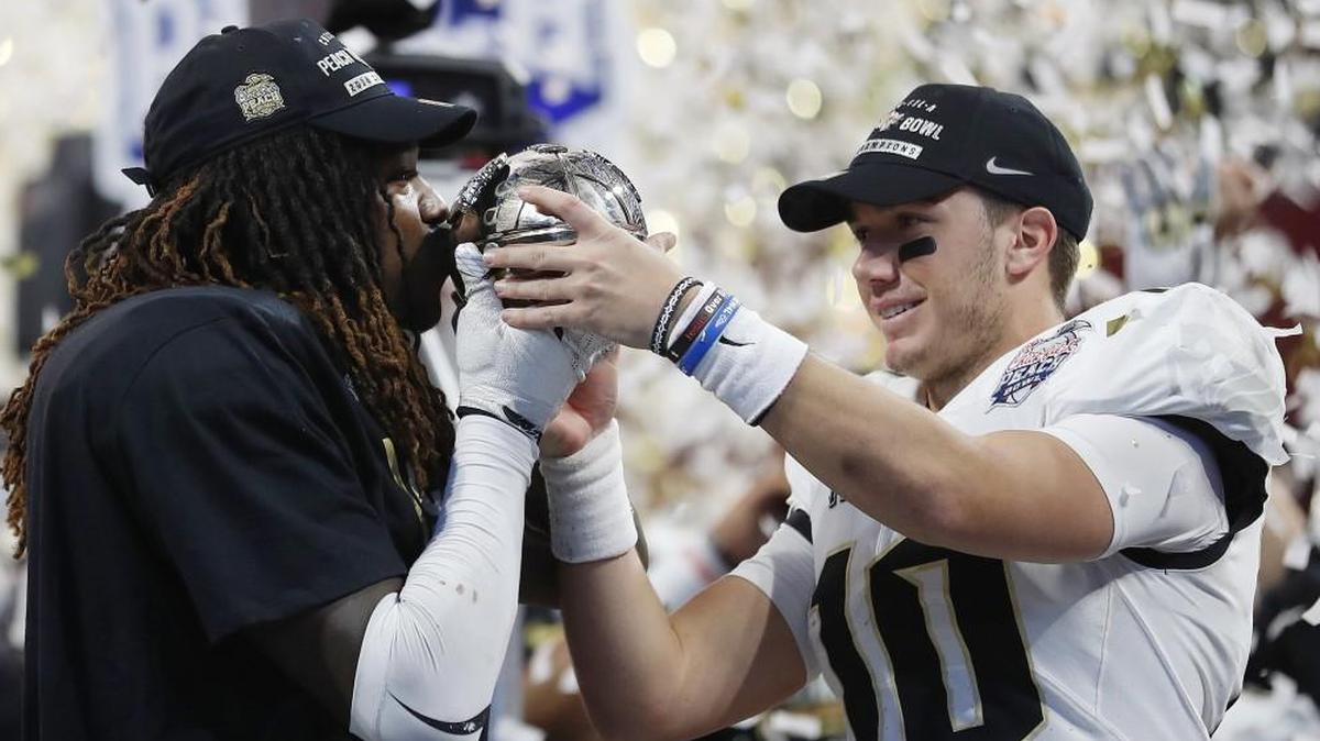 Central Florida linebacker Shaquem Griffin (left) kissed the championship trophy as Central Florida quarterback McKenzie Milton looks on after the Peach Bowl on Jan. 1 in Atlanta. Central Florida won 34-27.