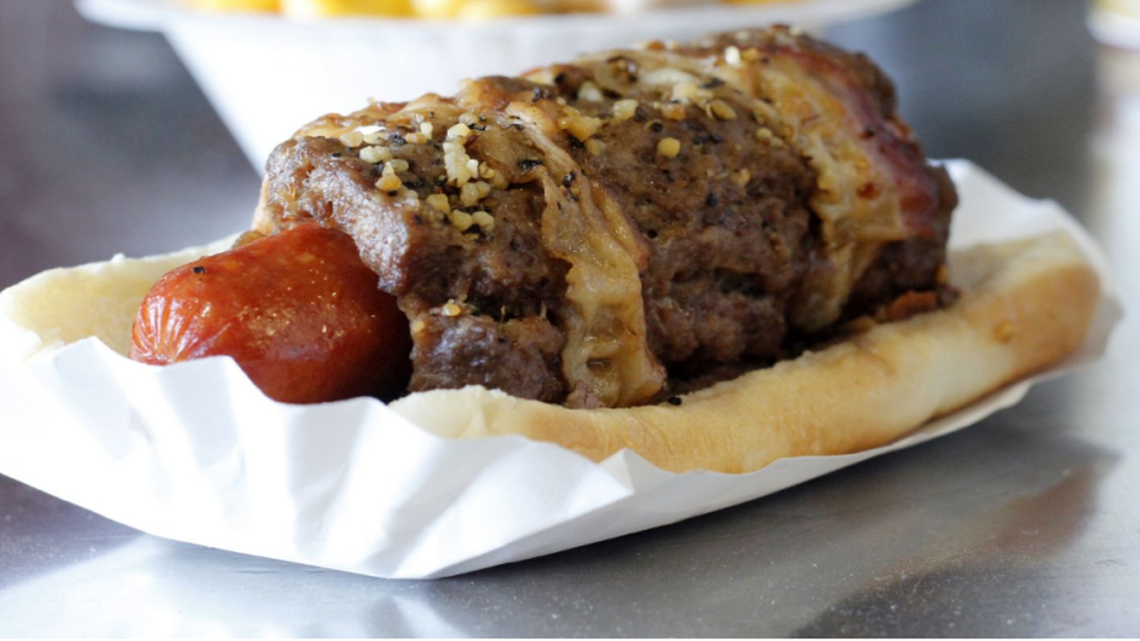 It’s name: The Triple Play Dog. It is a hot dog, wrapped with a hamburger, which is then wrapped in bacon.
