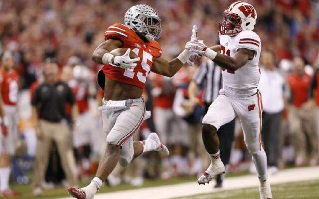 
Ohio State running back Ezekiel Elliott, with only one shoe, tried to hold off Wisconsin safety Lubern Figaro on a long second-half run in the Big Ten championship game on Saturday.
