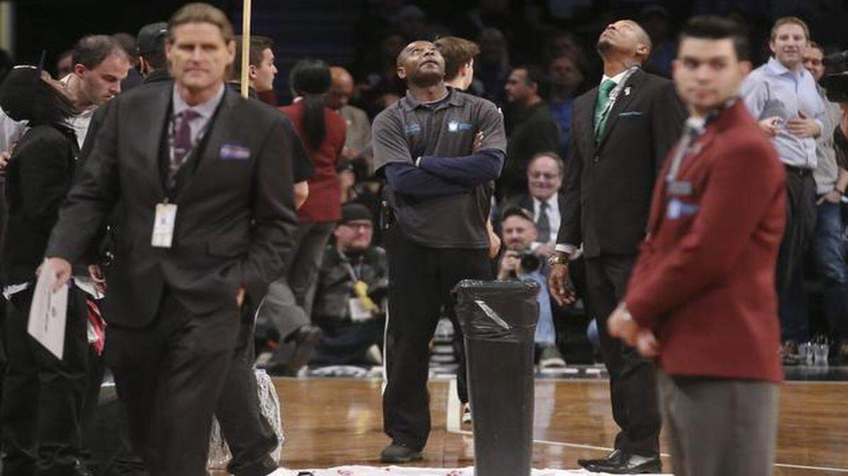 
Floor attendants look up at a roof leak causing a delay in the first half an NBA basketball game between the Brooklyn Nets and Miami Heat at the Barclays Center on Tuesday
