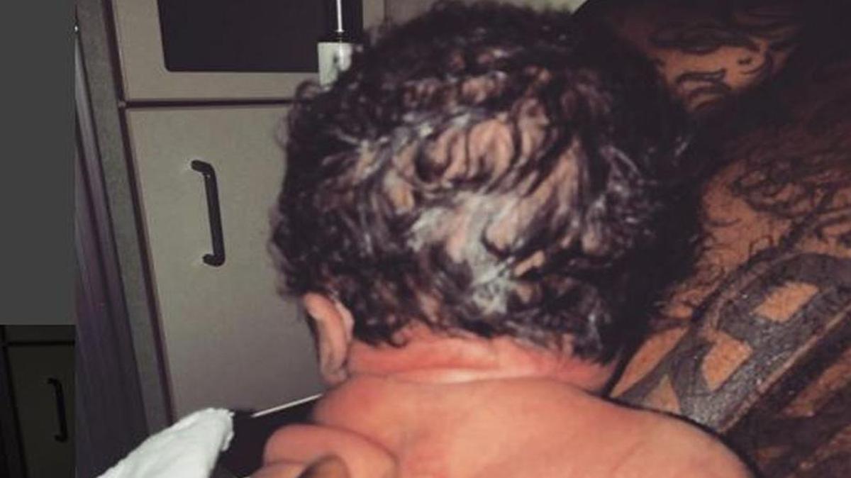 That appears to be a baby being held by someone in a kitchen.