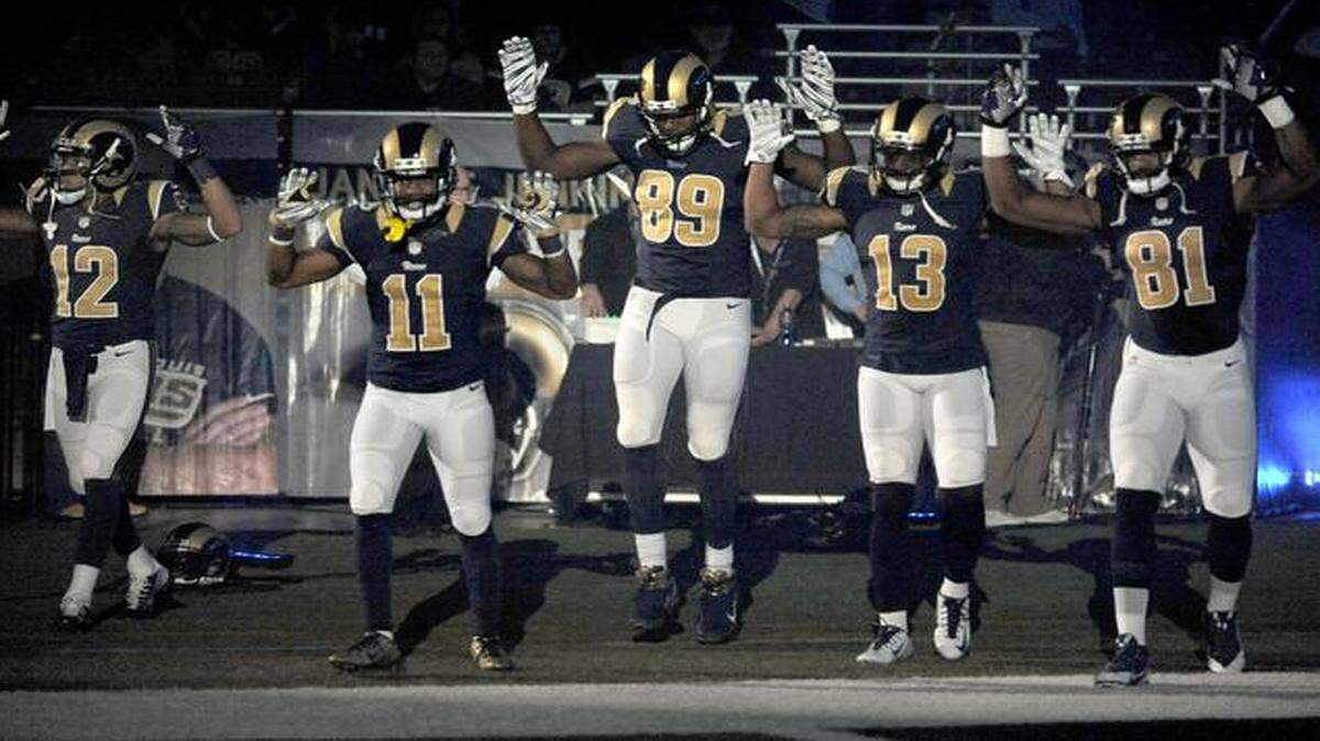 
St. Louis Rams players, from left; Stedman Bailey (12), Tavon Austin (11), Jared Cook, (89) Chris Givens (13) and Kenny Britt (81) raise their arms in awareness of the events in Ferguson, Mo., as they walk onto the field during introductions before an NFL football game against the Oakland Raiders in St. Louis. 
