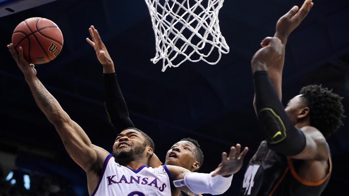 Kansas’ Frank Mason was fouled hard and went to the floor after this drive by Texas’ Kerwin Roach and Prince Ibeh during the second half of Saturday’s game at Allen Fieldhouse. KU beat Texas, 76-67.
