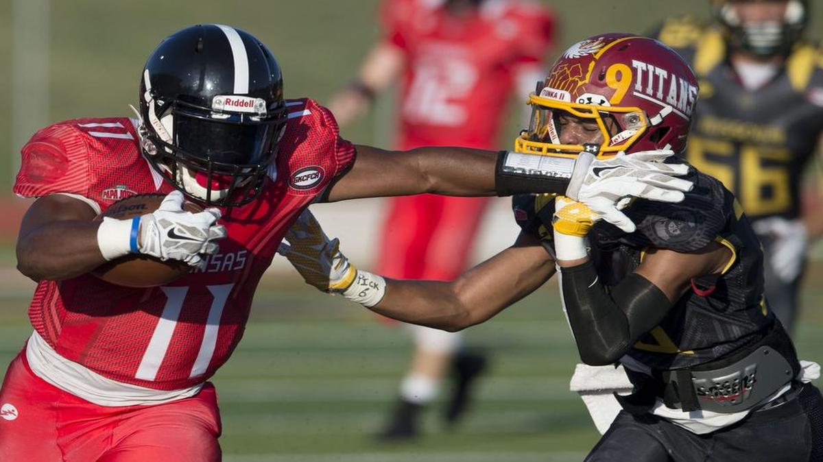 Running back JD Woods (left) of the Kansas All-Stars looked to get around Missouri All-Stars defensive back Tyrique Bennett of Winnetonka High School during first-quarter action last week of the Papa John’s Kansas vs. Missouri All-Star Game at Blue Springs High School.